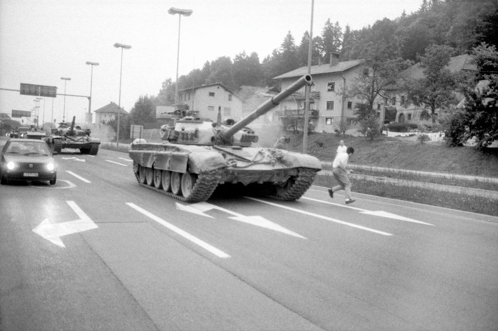 Tank sredi ceste, moški odskoči izpred tanka.