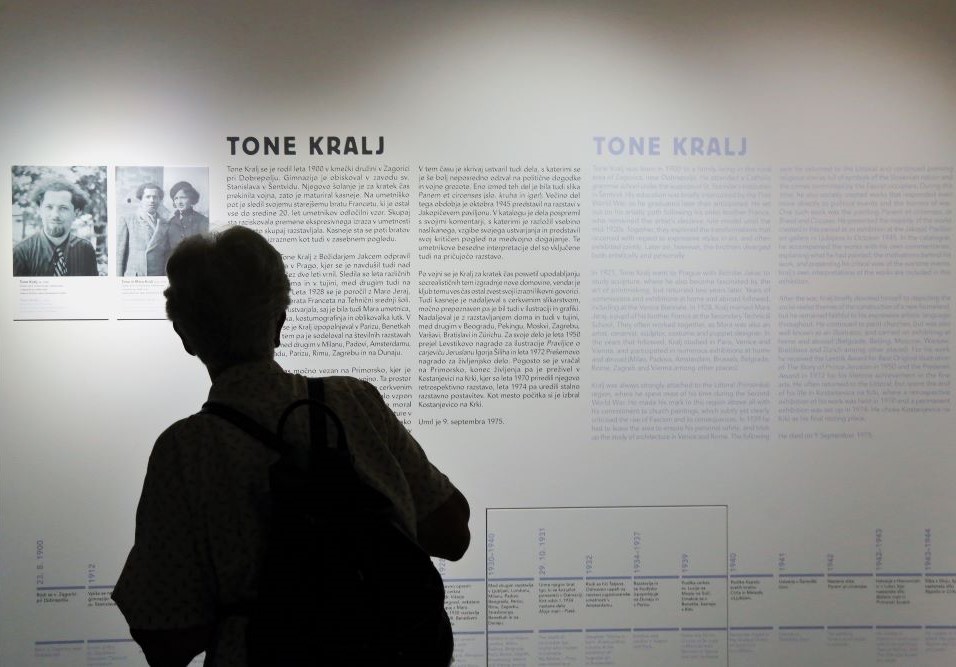 Obiskovalec na razstavi Kruha in iger stoji pred razstavnim panojem.