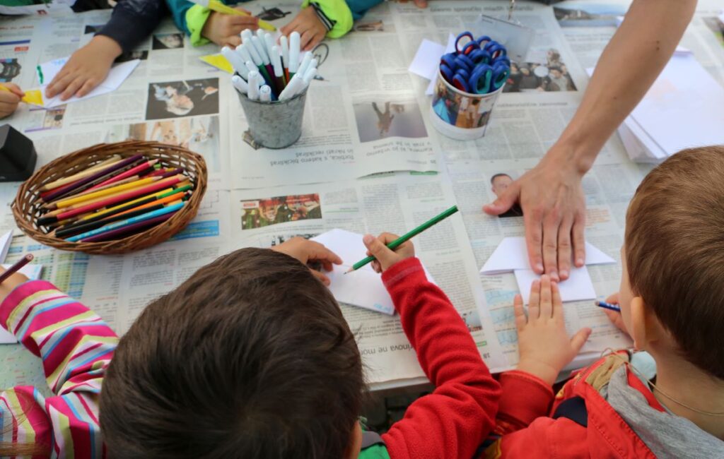 Otroci rišejo in izrezujejo podobe iz barvnega papirja.