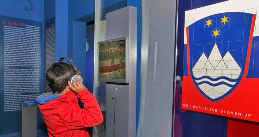 Otrok s slušalkami na razstavi gleda v ekran.