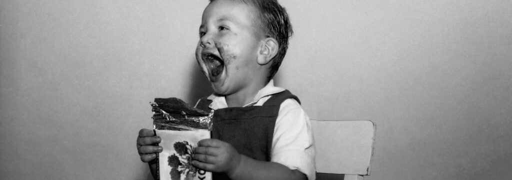 Nasmejan otrok s čokolado v roki in okoli ust.