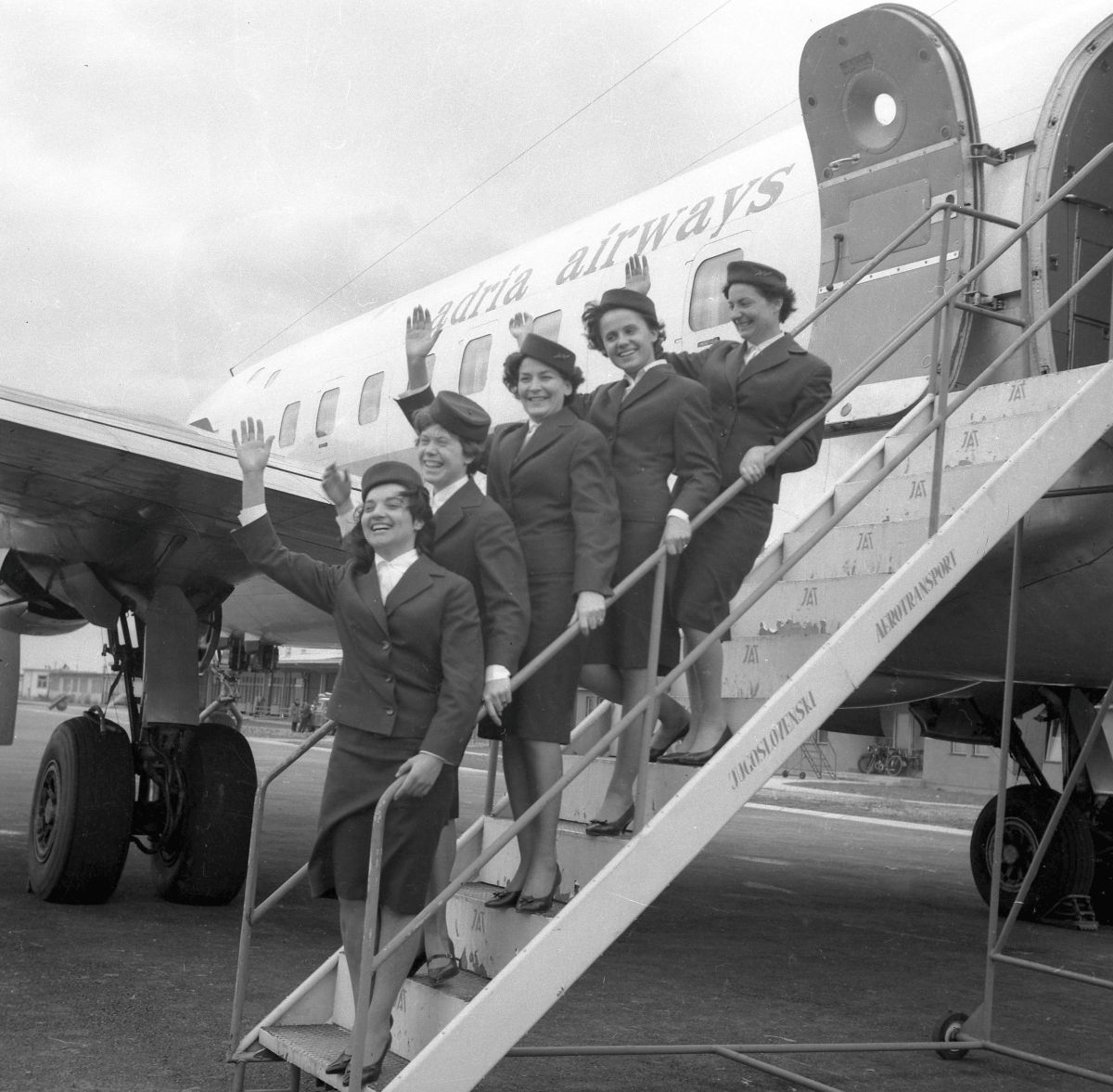 Stevardese na letalskih stopnicah mahajo.