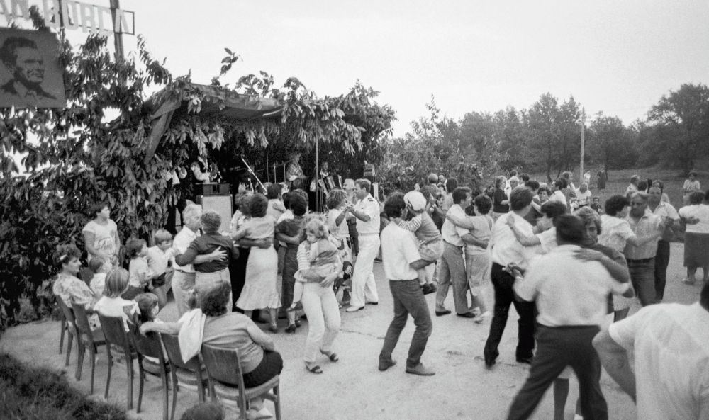 Osebe plešejo in sedijo na veselici.