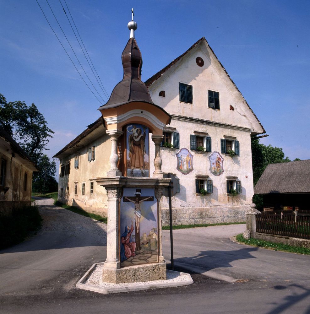 Hiša in znamenje pred njo.