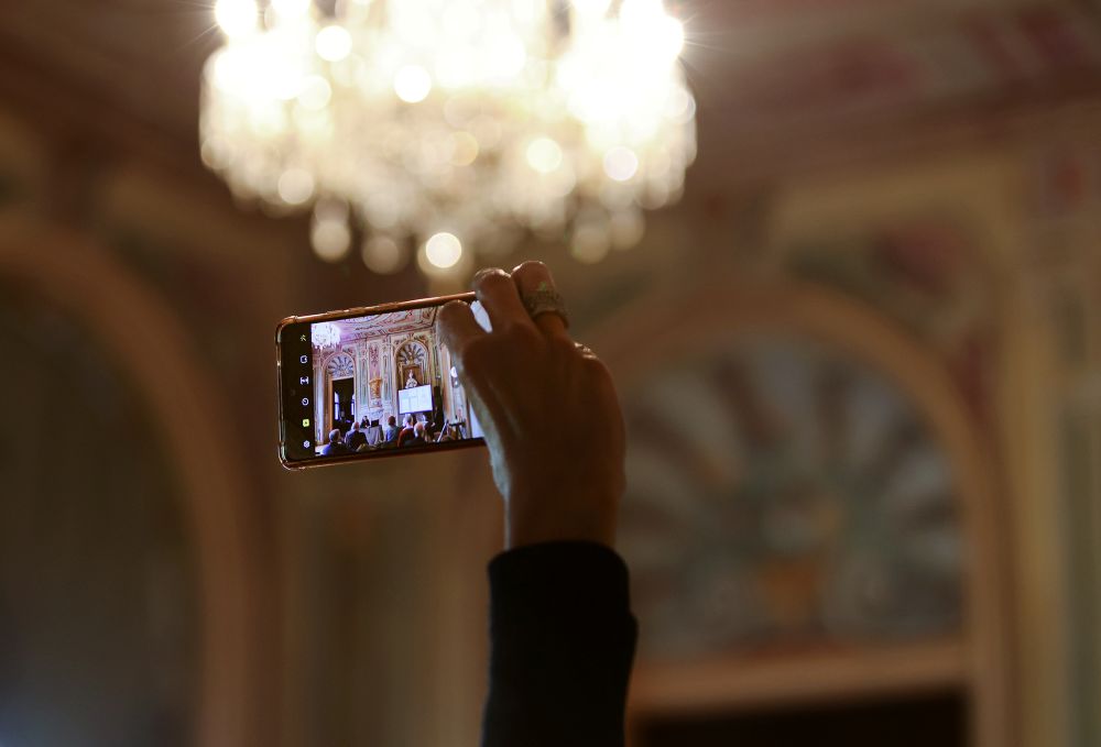 Ženska drži v roki mobilni telefon in fotografira.