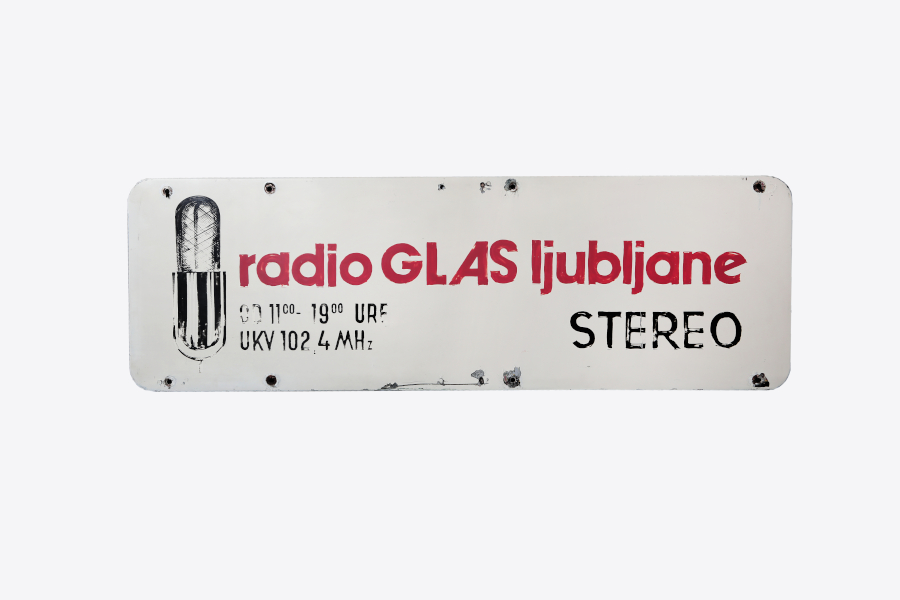 Na tabli je napis Radio glas Ljubljane, pod tem so napisane frekvence ter zraven slika mikrofona.