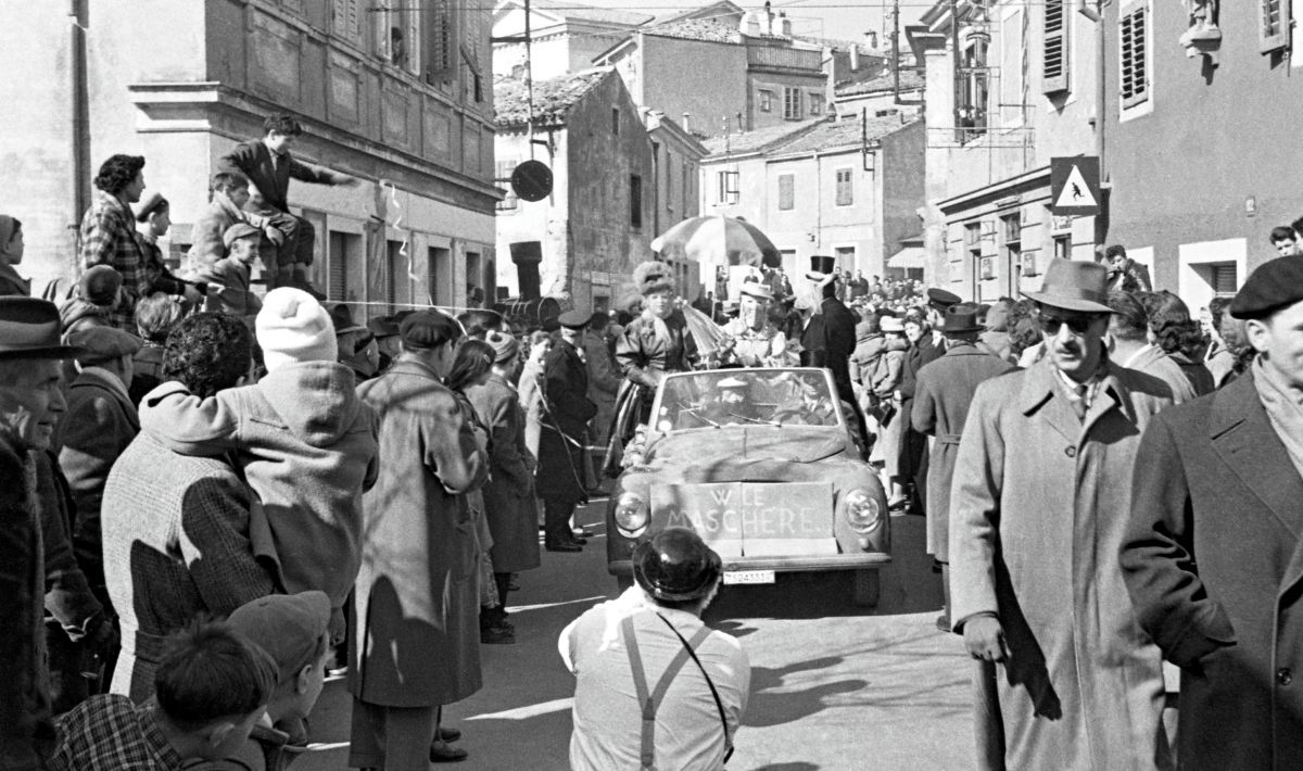 Na fotografiji avto – kabriolet, v katerem se peljejo pustne maske
