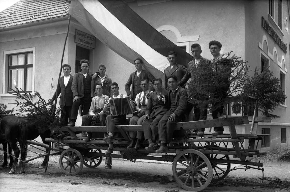Skupinska fotografija nabornikov iz Moravč na s smrečjem okrašenem vozu. Nad njimi je razgrnjena jugoslovanska trobojnica. Skupina je fotografirana pred fotografovo hišo. V ozadju je nad vhodnimi vrati napis »Lampič Peter fotograf«.