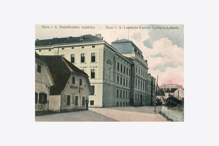 Fotografija prikazuje stavbo vojašnice, ki je bila zgrajena leta 1906 ob Poljanski cesti. V ozadju večnadstropne stavbe se vidi ljubljanski grad, pred vojašnico pa stojita starejši enonadstropni stavbi.
